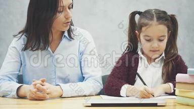 一个女学生和他的母亲坐在桌子旁写作业。 在这段时间里，妈妈从相框里出来